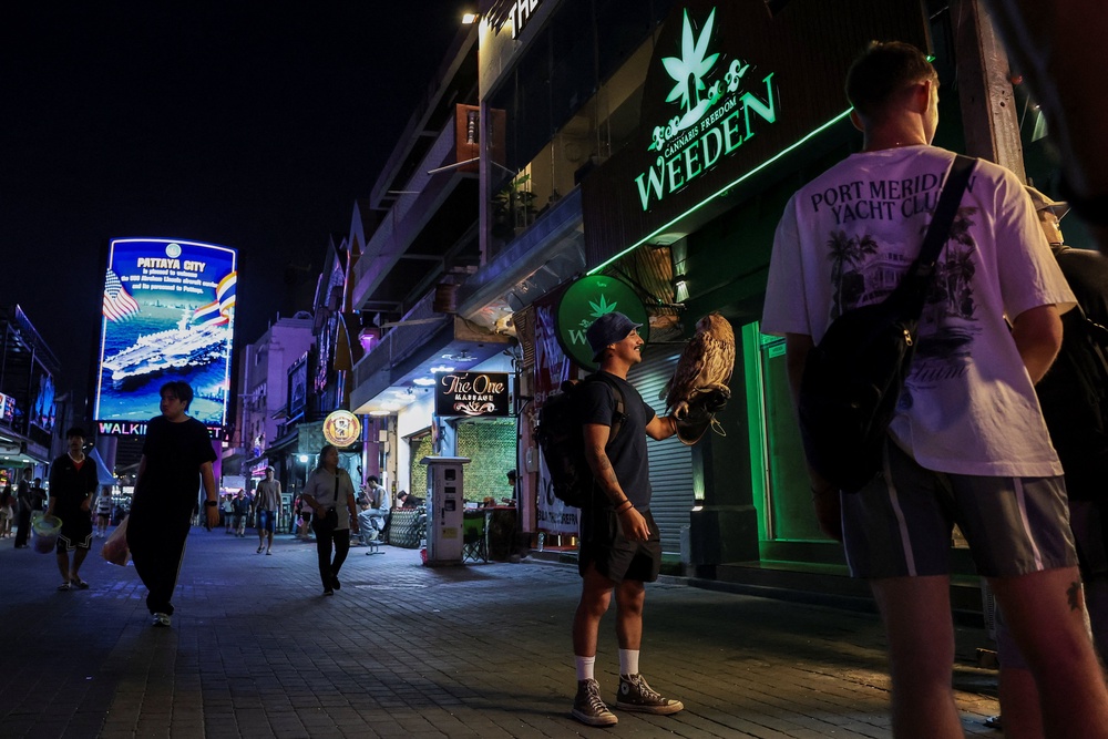 US service member from the USS Abraham Lincoln poses for a picture with an owl with an LED display welcoming them at Walking Street in Pattaya (Reuters)
