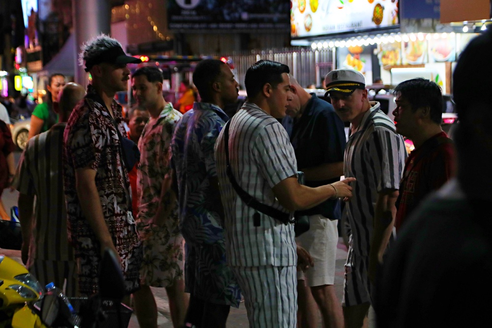 People walk in a tourist district as the USS Abraham Lincoln aircraft carrier arrives at Laem Chabang Port (Getty)