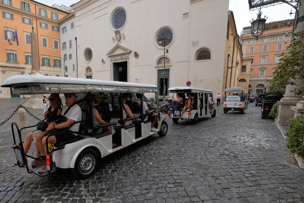 A flotilla of golf carts carrying tourists travels past the Basilica of Santa Maria sopra Minerva in Rome, Thursday, Aug. 27, 2026, as city officials move to regulate the rapidly growing industry amid complaints about congestion, illegal parking, and overtourism (AP Photo/Gregorio Borgia) (Copyright 2026. The Associated Press. All rights reserved)