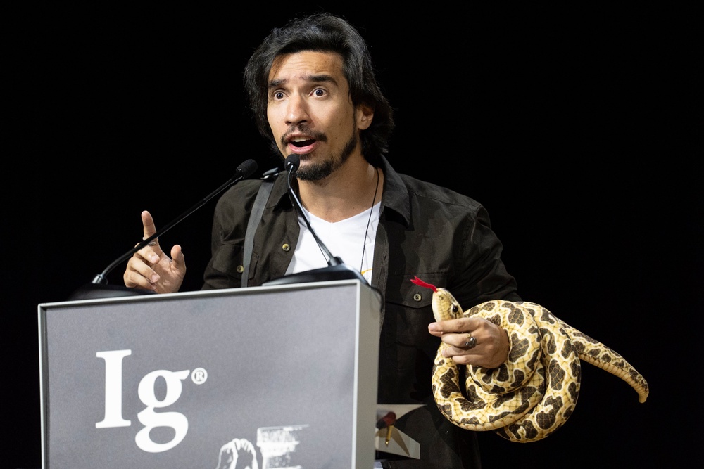 Ig Nobel winner João Miguel Alves Nunes speaks with a toy snake wrapped around his arm during the awards ceremony in Zurich on 3 September 2026 (AP)