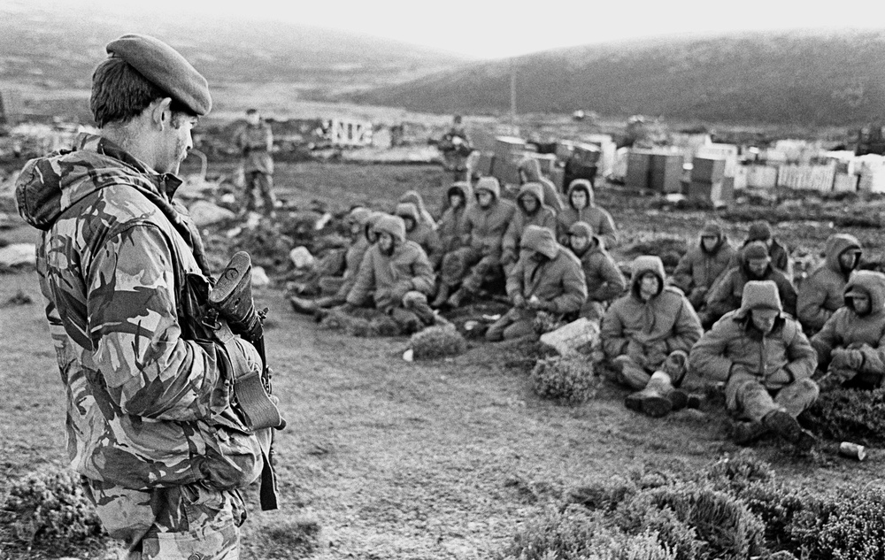 Argentinian soldiers captured at Goose Green guarded by a Royal Marine - June 2, 1982 (PA)