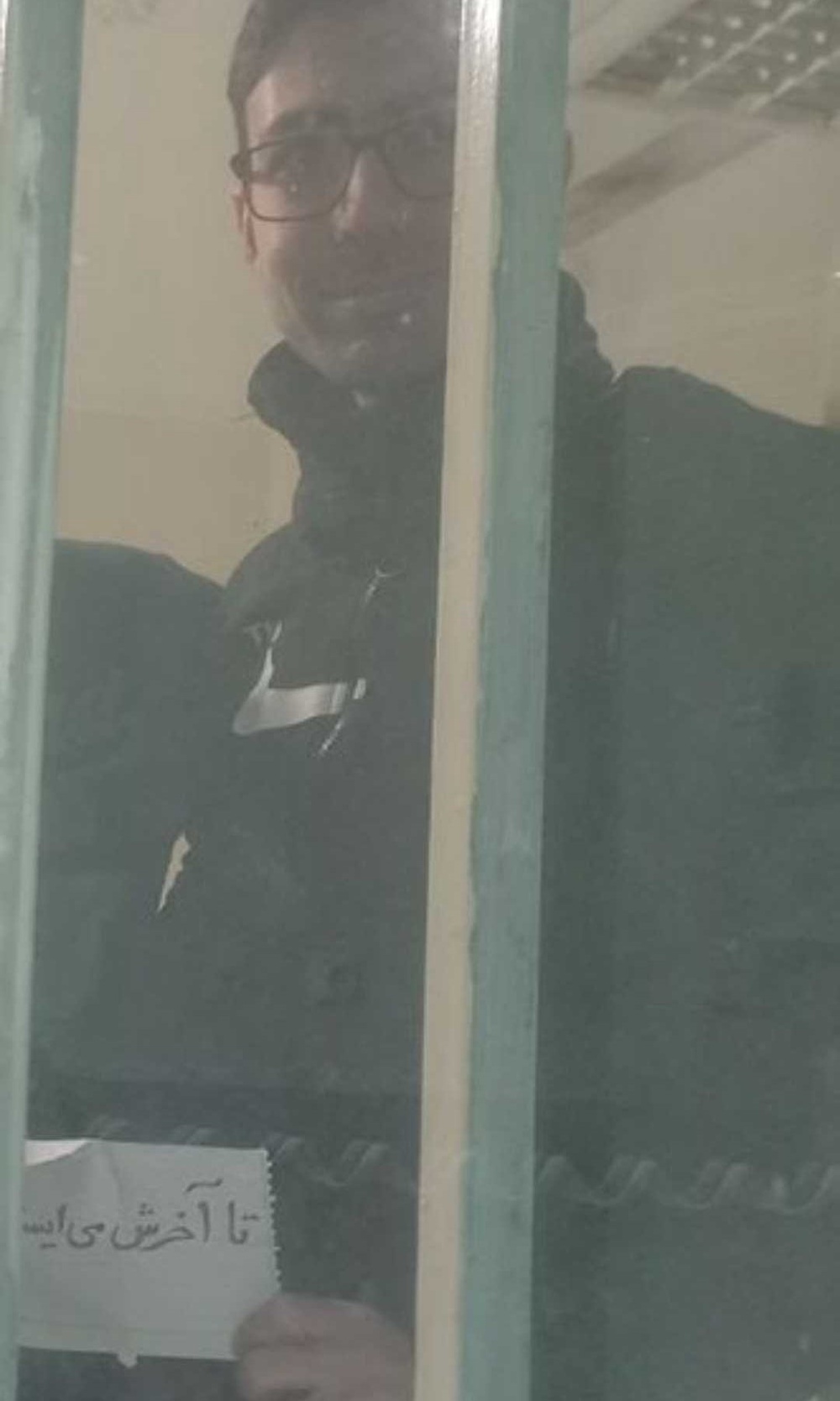 In this image, which is believed not to have been previously published, executed political prisoner and PMOI member Vahid Baniamerian holds a note reading: 'We stand until the end. January 2026. Evin Prison' (Handout)