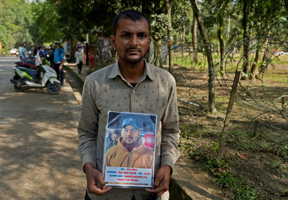 Krishna Poudel, 34, the brother of Ishwor Poudel, a missing worker at Trishuli-1 Hydropower Project, with a photograph of Ishwor outside the Maithili Barrack in Nuwakot District, Nepal (Reuters)