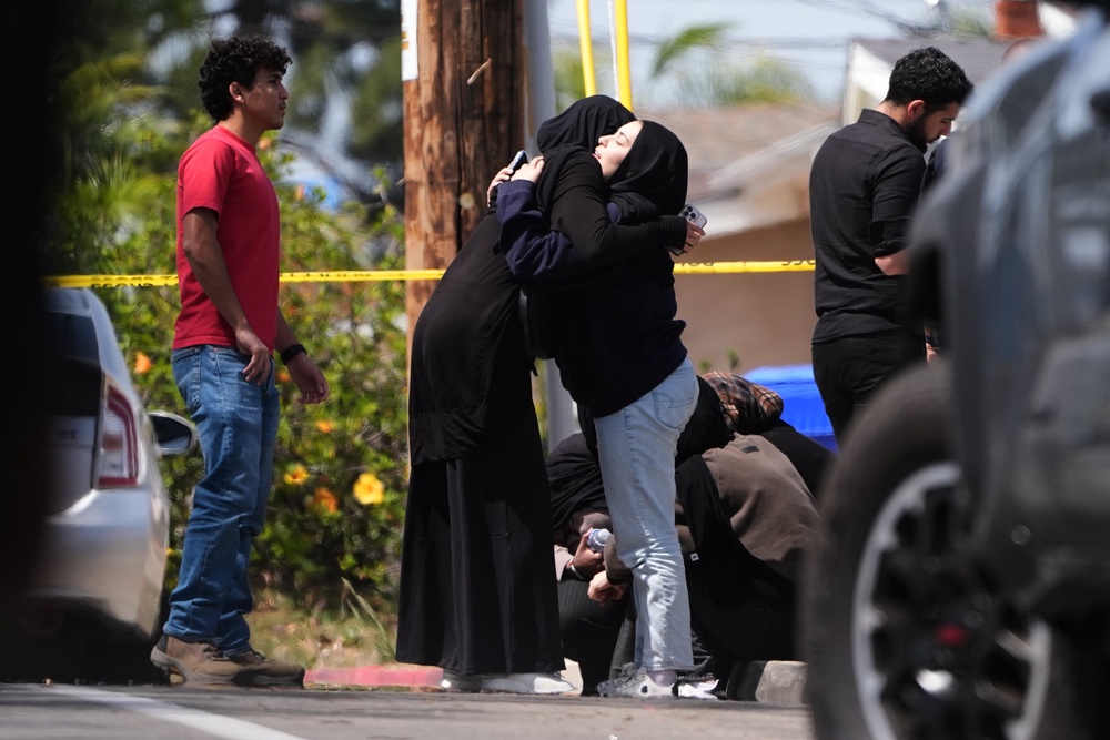 Members of the public embrace near the scene of a shooting on May 18 (AP)