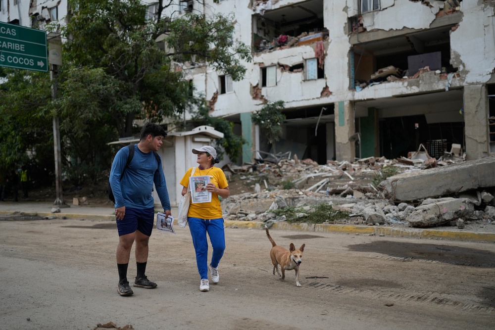 Pedro Gomez, left, walks through La Guaira, Venezuela, with a friend (AP)