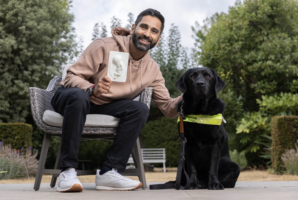 Amit Patel, a father with a visual impairment, with his guide dog Quark, holding a tactile sonogram created from a traditional 20-week ultrasound scan (Matt Alexander Media Assignments/PA) (PA Wire)