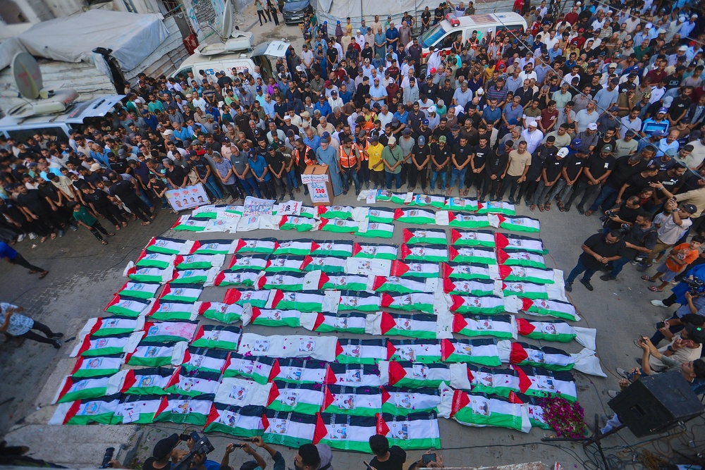 A crowd surrounds rows of bodies during a funeral ceremony in Zeitoun neighborhood of Gaza City, Gaza (AFP/Getty)