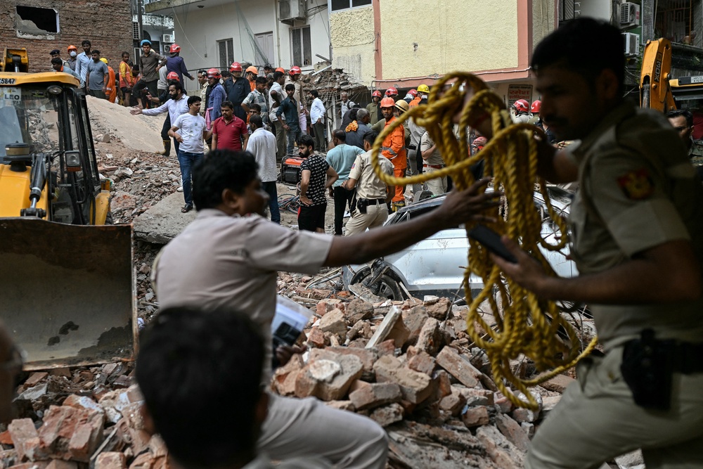 Security personnel cordon off the area as a bulldozer clears debris at the site following a building collapse in the Satya Niketan area in New Delhi (AFP/Getty)