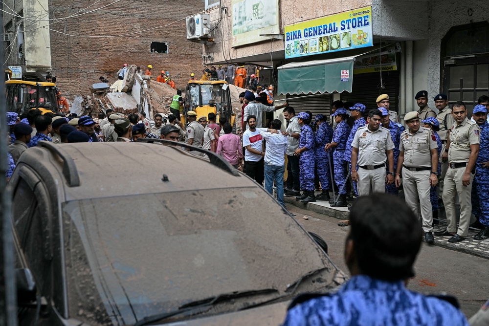 Security personnel stand guard along a street as rescue personnel conduct a search operation at the site following a building collapse in the Satya Niketan area in New Delhi on 6 September 2026 (AFP/Getty)