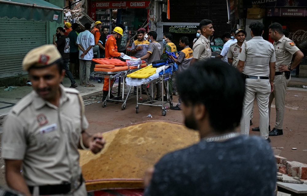 Paramedics prepare stretchers as rescue personnel conduct a search operation for survivors at the site of a building collapse in the Satya Niketan area in New Delhi on 6 September 2026 (AFP/Getty)