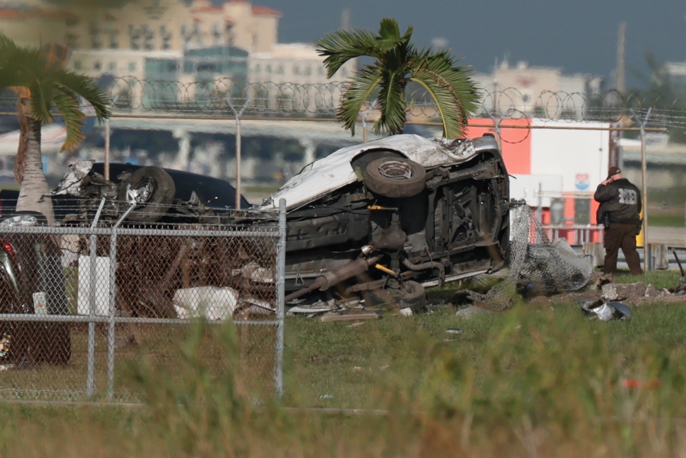 Investigators walk near damaged vehicles at Miami International Airport (Getty)