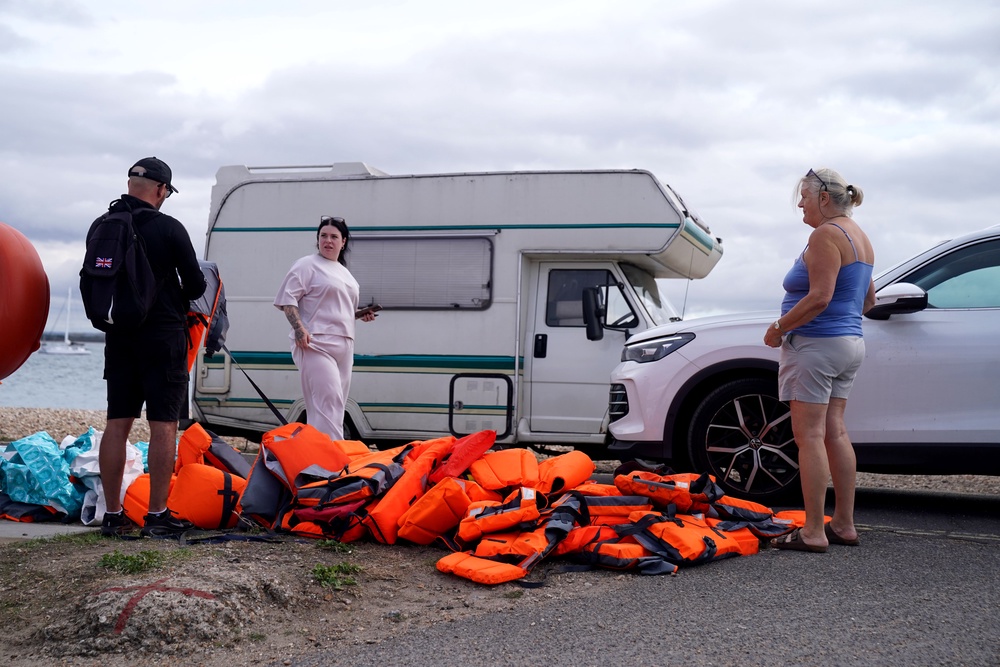Local resident Sue Dewey (right), 68, collects some of the discarded life jackets at Eastney Point (PA)