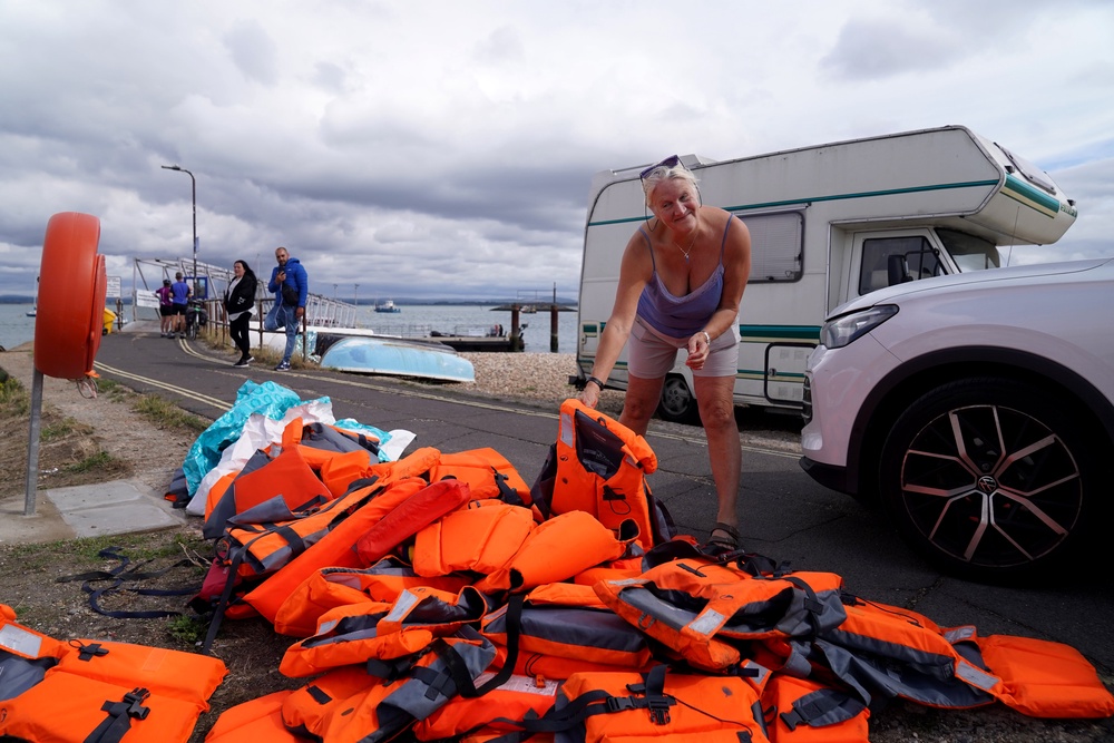 Local resident Sue Dewey, 68, collects some of the discarded life jackets following Sunday night's operation in Portsmouth. Local leaders say the city is not suited for such landings. (PA)