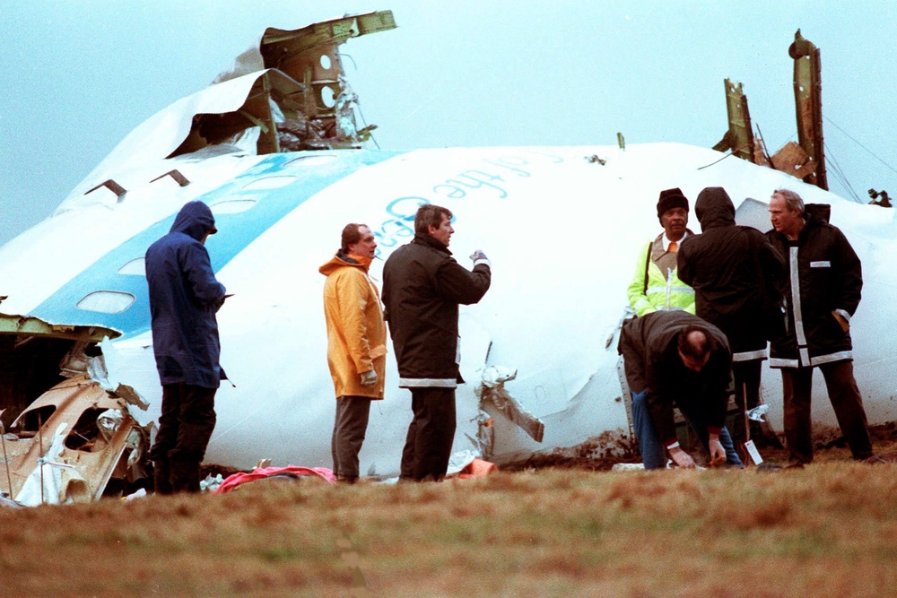 Unidentified crash investigators inspect the nose section of the crashed Pan Am flight 103, a Boeing 747 airliner in a field near Lockerbie, Scotland, Dec. 23, 1988 (AP)