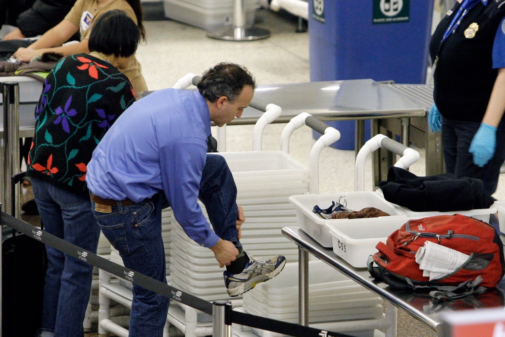 An airline passenger pulls off his shoes to be scanned as he prepares to go through a security checkpoint at Seattle-Tacoma International Airport (Copyright 2010 The Associated Press. All rights reserved.)