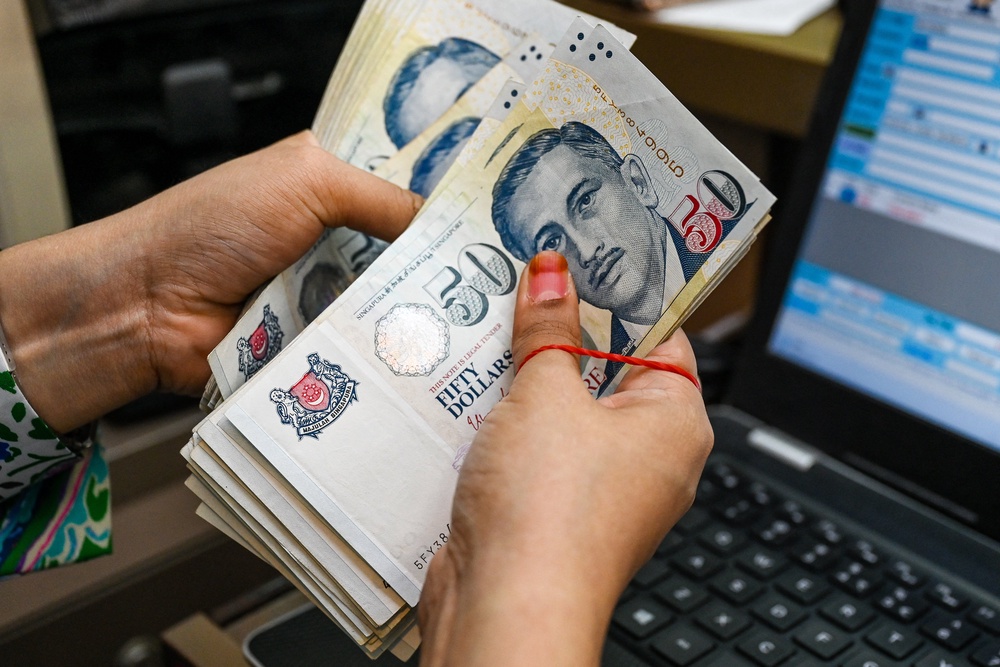 A staff counts Singapore dollar currency notes at a money changer booth at Raffles Place financial business district in Singapore (AFP/Getty)