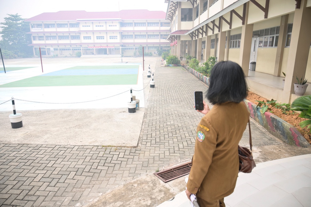 A teacher communicates with students on her phone while standing in the compounds of her school seen shrouded in smog after local authorities mandated remote learning due to haze from land and forest fires in Pontianak, West Kalimantan (AFP/Getty)