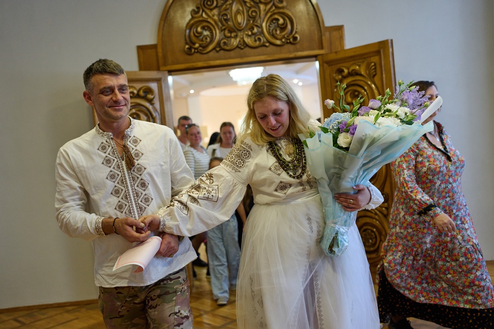 Newly-married couple Liudmyla Ryzhak, right, and her husband Leonid Ryzhak leave after getting married, following a Russian missile and drone attack (Associated Press)