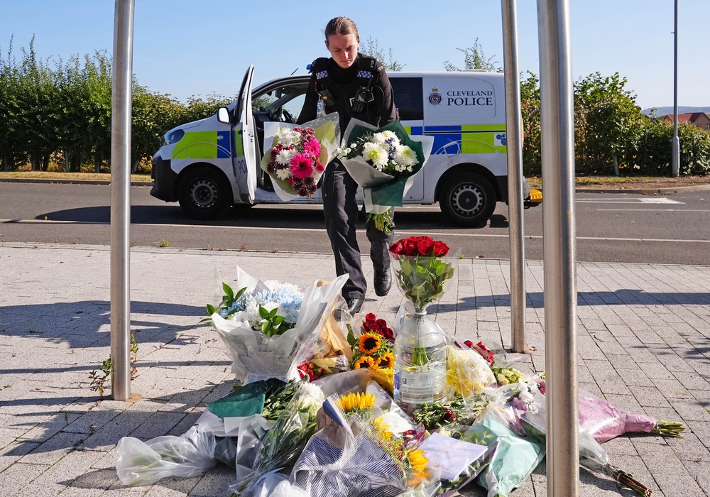 A police officer leaves flowers at the Cleveland Police HQ Memorial Garden in Middlesbrough (PA) (PA Wire)