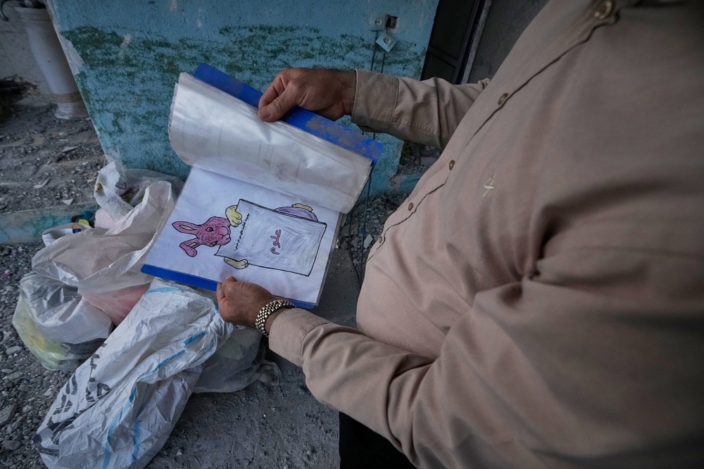 A volunteer holds a child's notebook recovered from the Shajareh Tayyebeh school (AP)