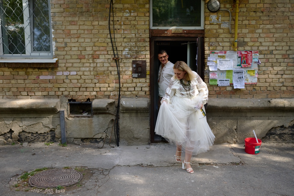 Liudmyla Ryzhak, right, and her fiancee Leonid Ryzhak leave a damaged residential building to go to their wedding ceremony, following a Russian missile and drone attack in Kyiv, Ukraine (AP)