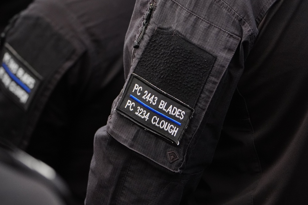A police officer wears a black armband embroidered with the names of two colleagues who were killed - Pc Blades and Pc Clough. (PA)