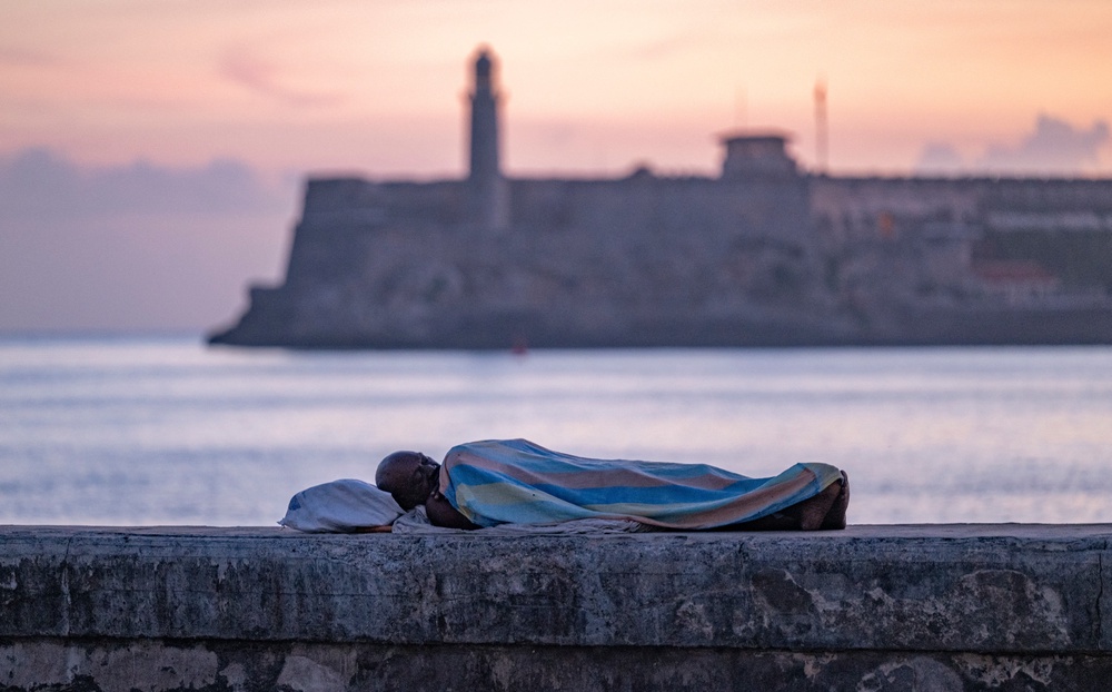 A person sleeps on the seafront wall at dawn in Havana on August 13, 2026. Many Cubans sleep in open-air spaces in search of relief from high temperatures and frequent power cuts (AFP via Getty Images)