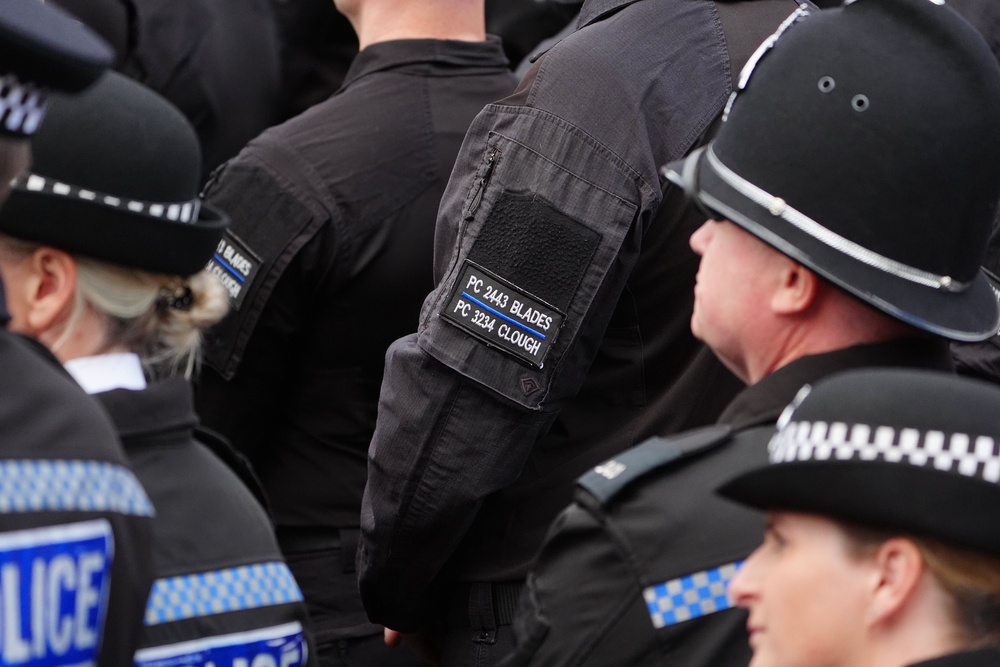 A police officer wears a black armband embroidered with the names of two colleagues who were killed (Owen Humphreys/PA) (PA Wire)