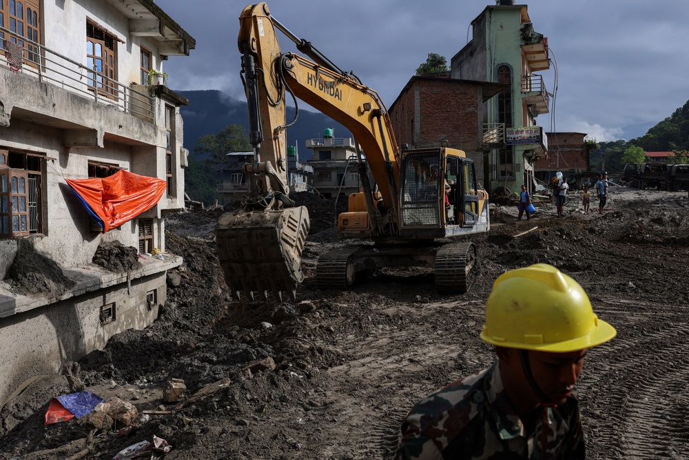 An excavator clears mud and debris from a road in Devighat, Nepal, on 10 September  2026 (Reuters)
