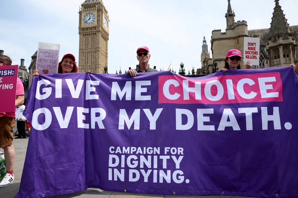 Supporters of the assisted dying law for terminally ill people hold a banner (Reuters)