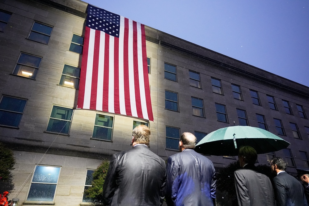 US secretary of defence Pete Hegseth, chairman of the Joint Chiefs, General Dan Caine and other officials, watch as the US flag is unfurled at the Pentagon (Manuel Balce Ceneta/AP) (AP)