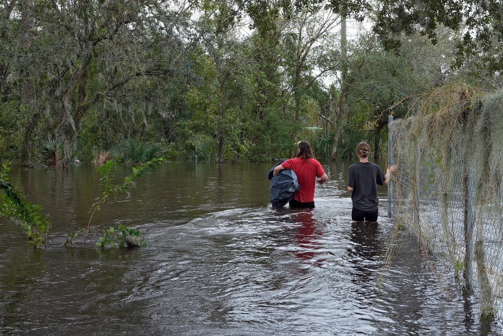 FILE - Connor Hughes and Kaylee Swenson walk through floodwaters from the Alafia River caused by Hurricane Milton, Oct. 11, 2024, in Lithia, Fla. (AP Photo/Chris O'Meara, File) (Copyright 2024 The Associated Press. All rights reserved.)