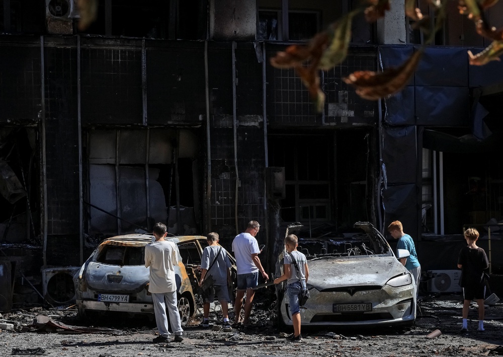 People look at burned cars near a hotel damaged during a Russian drone strike, amid Russia's attack on Ukraine, in the city of Chornomorsk, Odesa region (Reuters)