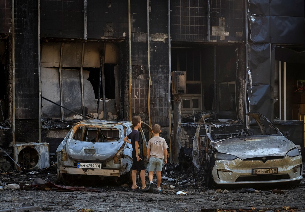 Children look at burned cars near a hotel damaged during a Russian drone strike, amid Russia's attack on Ukraine, in the city of Chornomorsk (Reuters)