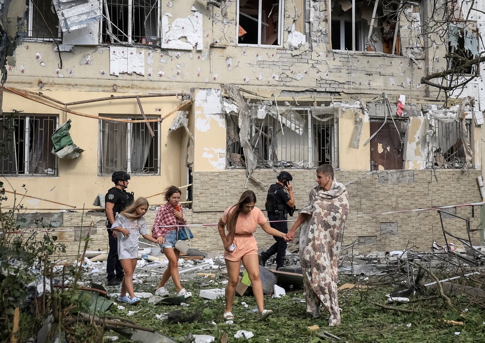 Residents leave a site of an apartment building damaged during a Russian drone strike (Reuters)