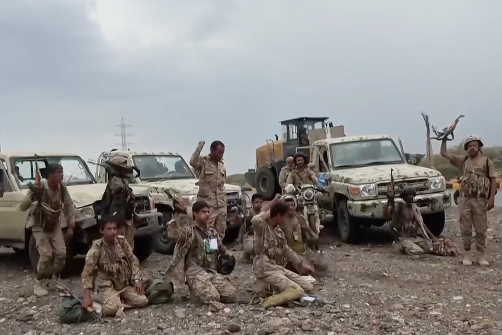 Houthi fighters chant after praying beside military vehicles during what the group says was their advance against Saudi-backed forces at an undisclosed location in southern Yemen, on 12 September (AP)