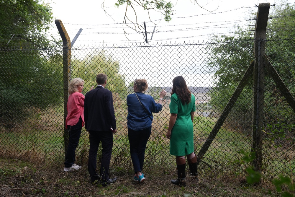 Shadow home secretary Chris Philp, shadow minister for women and equalities Joy Morrissey (right) and residents of Piddington look through the wire fence at the former military base (Joe Giddens/PA) (PA Wire)