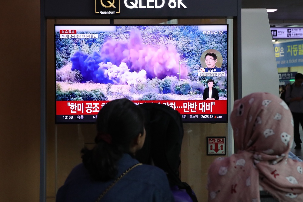 Commuters at the Seoul train station watch a TV news report about North Korea blowing up sections of inter-Korea roads on 15 October 2024 (Getty)