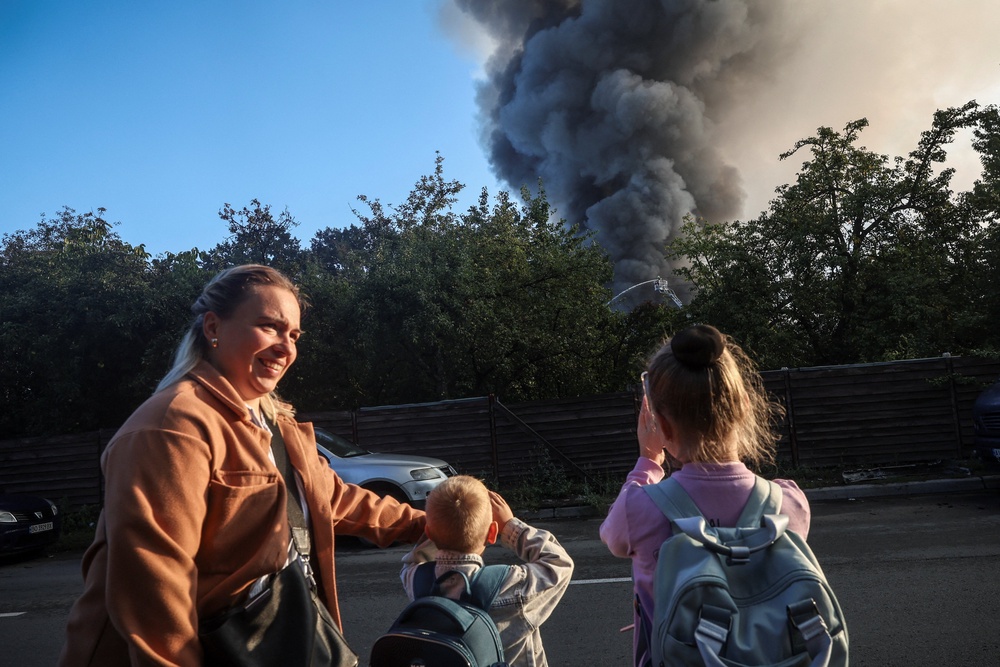 A woman and children stand near a site of a Russian drone strike as smoke rises from there, amid Russia’s attack on Ukraine, in Kyiv, Ukraine September 16, 2026. (Reuters)