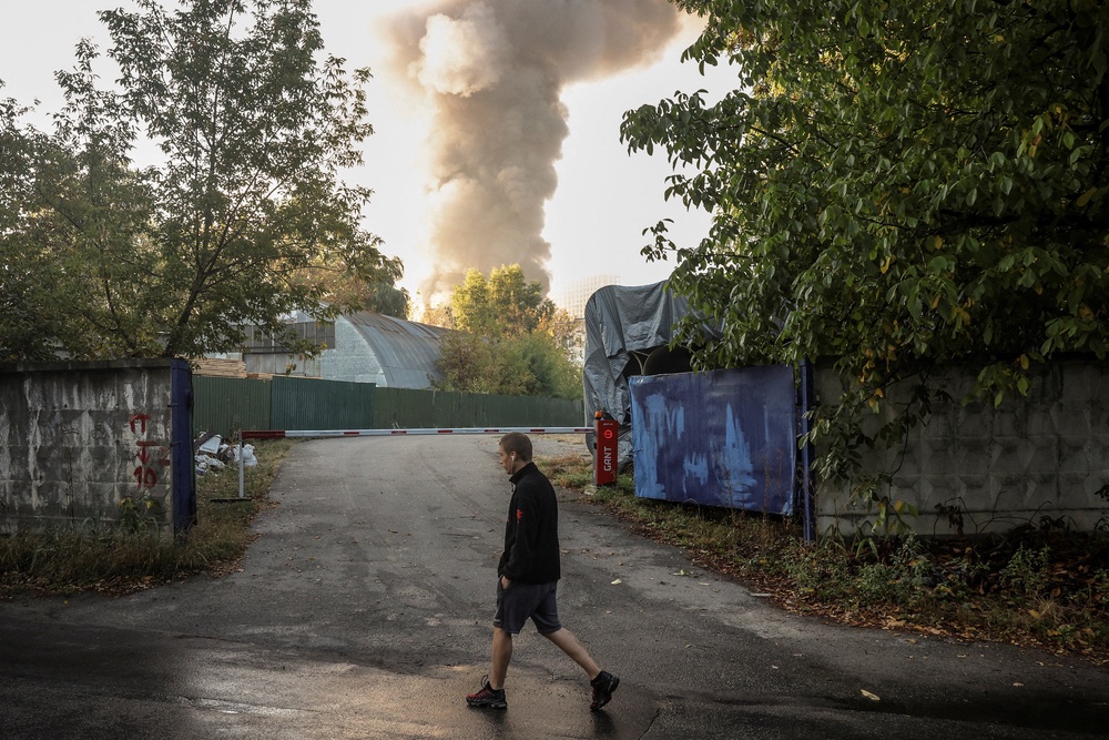 A person passes by the site of a Russian drone strike as smoke rises in the background, amid Russia’s attack on Ukraine, in Kyiv, Ukraine, September 16, 2026. (Reuters)