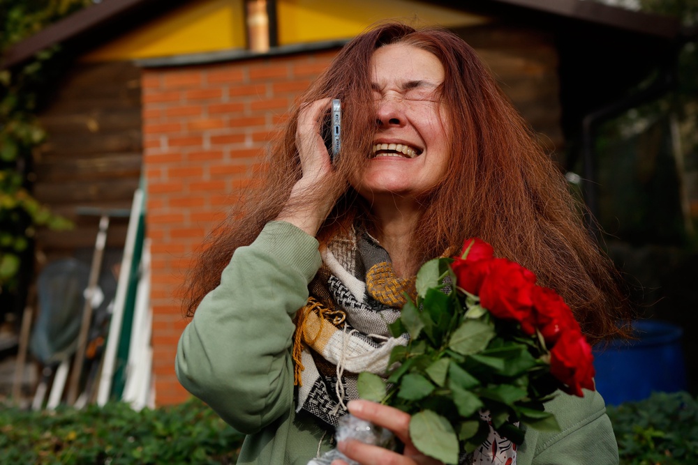 Tatsiana Kouzina, one of the released Belarusian prisoners reacts as she speaks on the phone upon her arrival in Vilnius, Lithuania (AP)