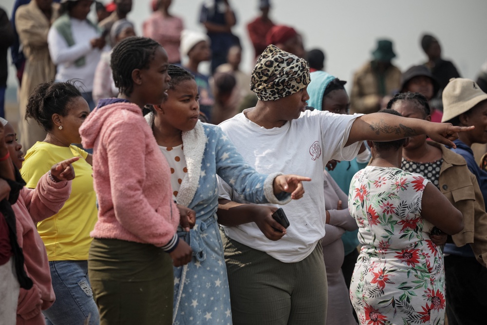 People gather and point in the direction of the crime scene where the body of a woman was discovered in Boksburg on September 17, 2026. (AFP/Getty)