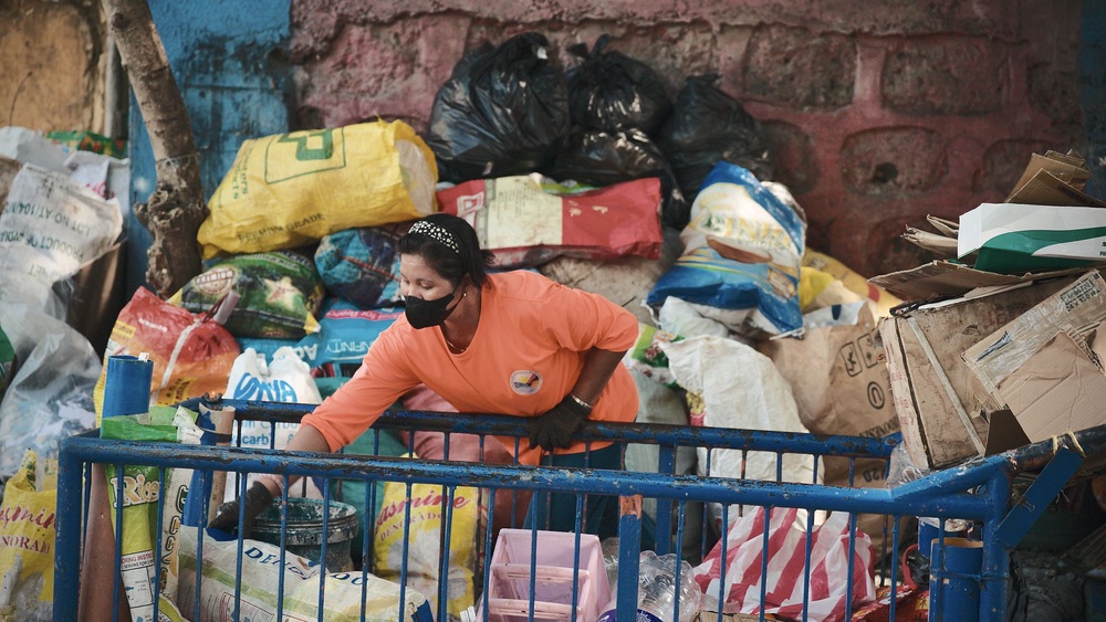 A waste worker sorts recyclables by hand in Manila (Mother Earth)