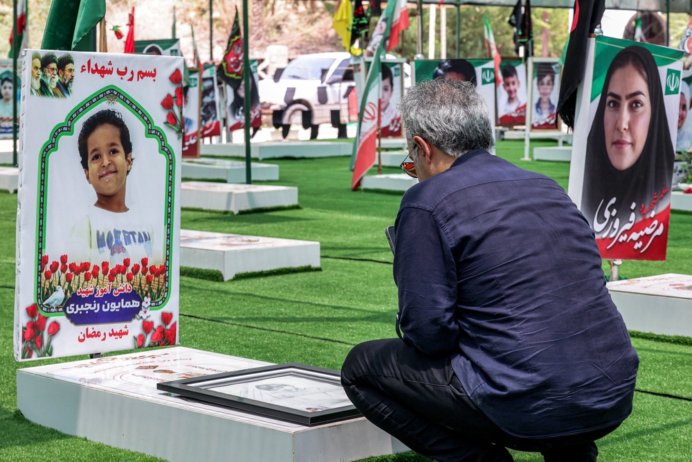 A man visits one of the graves of people and children killed during the strike on the primary school (AFP/Getty)