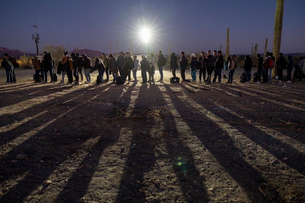 Immigrants line up at a remote U.S. Border Patrol processing center after crossing the U.S.-Mexico border on December 07, 2023 in Lukeville, Arizona (Getty Images)
