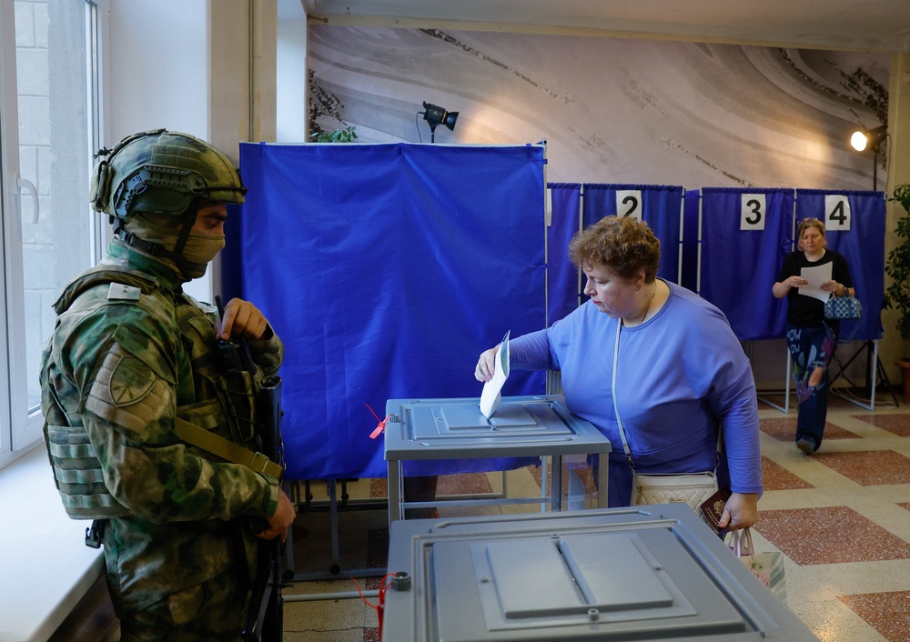 A woman casts her ballot next to a serviceman securing a poling station during Russia's parliamentary elections, in the course of Russia-Ukraine conflict in Donetsk, Russian-controlled Ukraine, September 18, 2026. (Reuters)