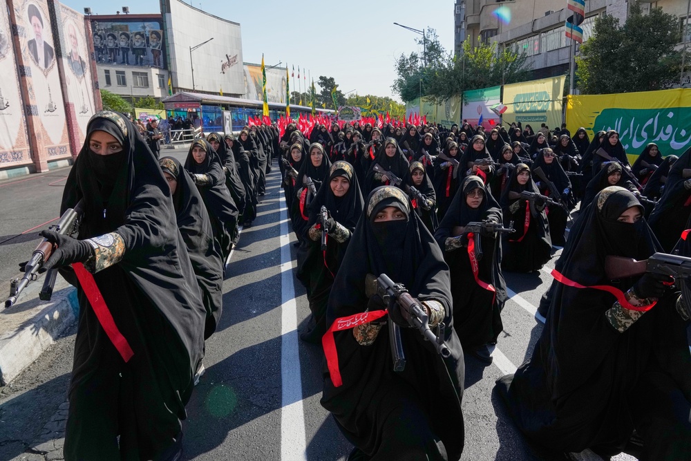 Women affiliated with Iran's Revolutionary Guard carry rifles as they stand during the state-organized “Janfada” march (AP)