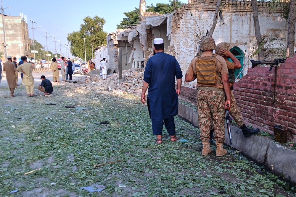 In this photo taken with a smartphone, army soldiers and local residents gather at the site of a powerful bomb exploded at a mosque in Kohat, in northwestern Pakistan (AP)