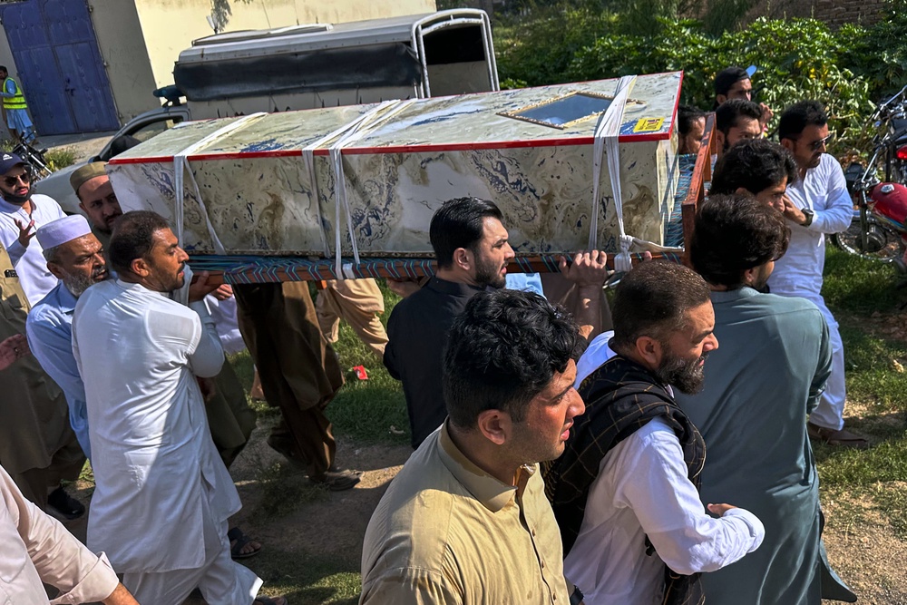 Mourners carry the casket of a victim who was killed in Friday's suicide bombing at a mosque, for a funeral in Kohat, in northwestern Pakistan (AP)