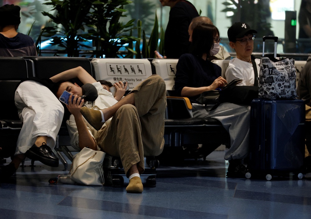 Passengers rest at the Haneda airport as many flights are delayed and cancelled due to Typhoon Dujuan (Reuters)